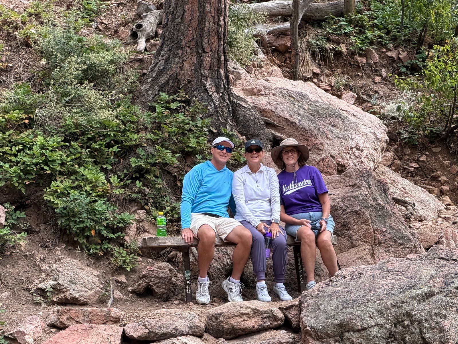 Three hikers resting on a wooden bench
