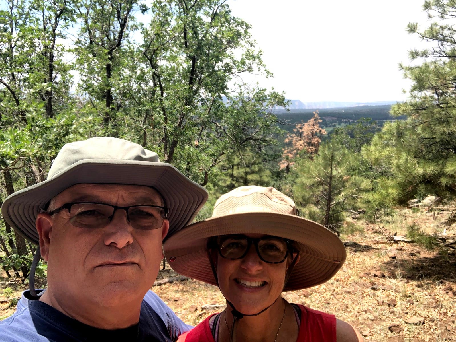 Chuck and Leslie selfie on a forest hike with a distant mesa