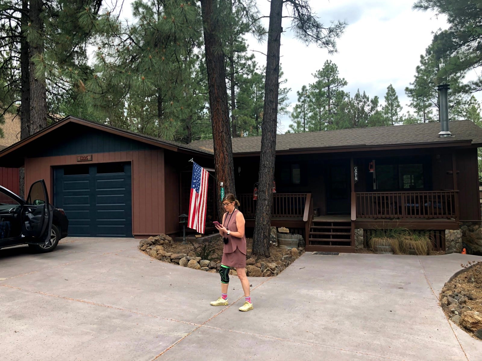Leslie walking in front of a cabin among ponderosa pines