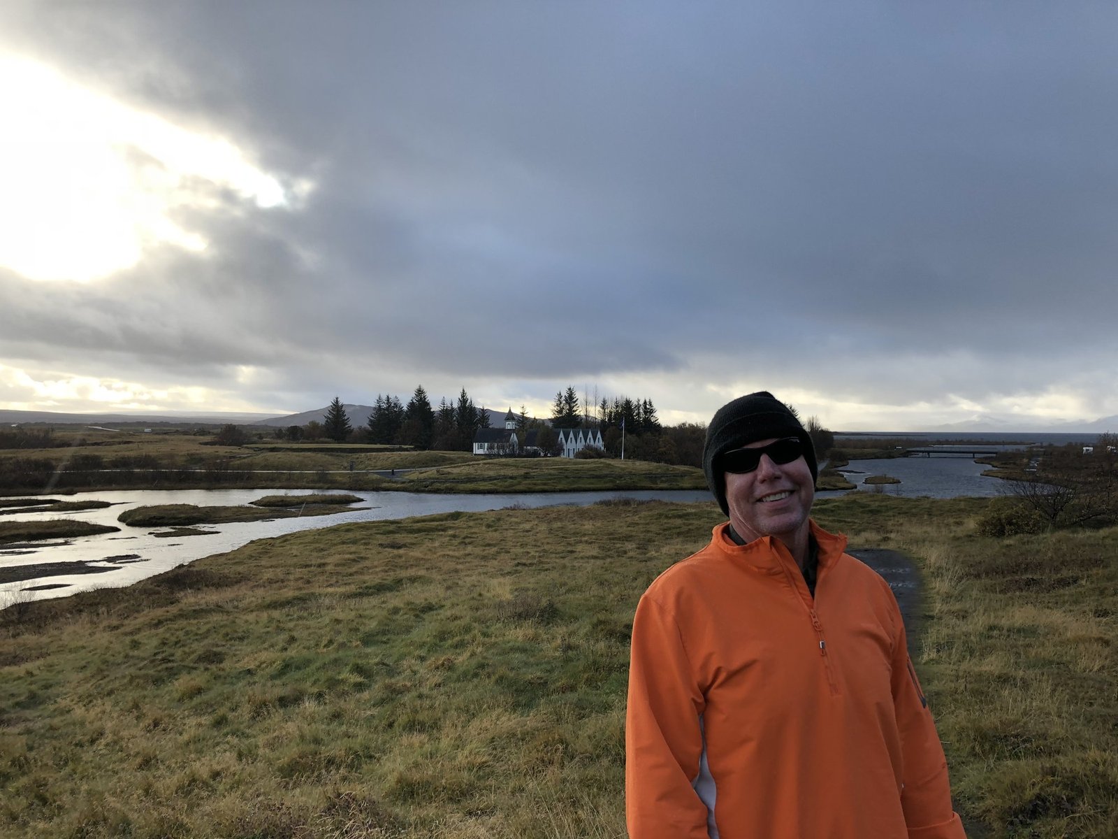 Chuck in orange fleece with valley and white buildings behind