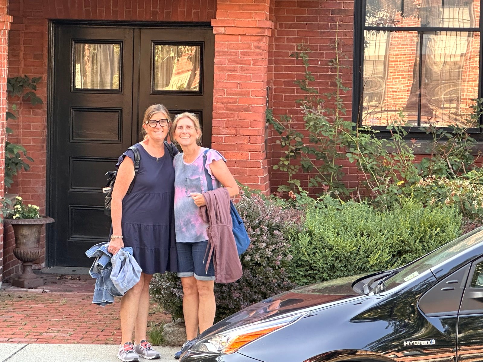 Two friends smiling in front of a brick building in Camden