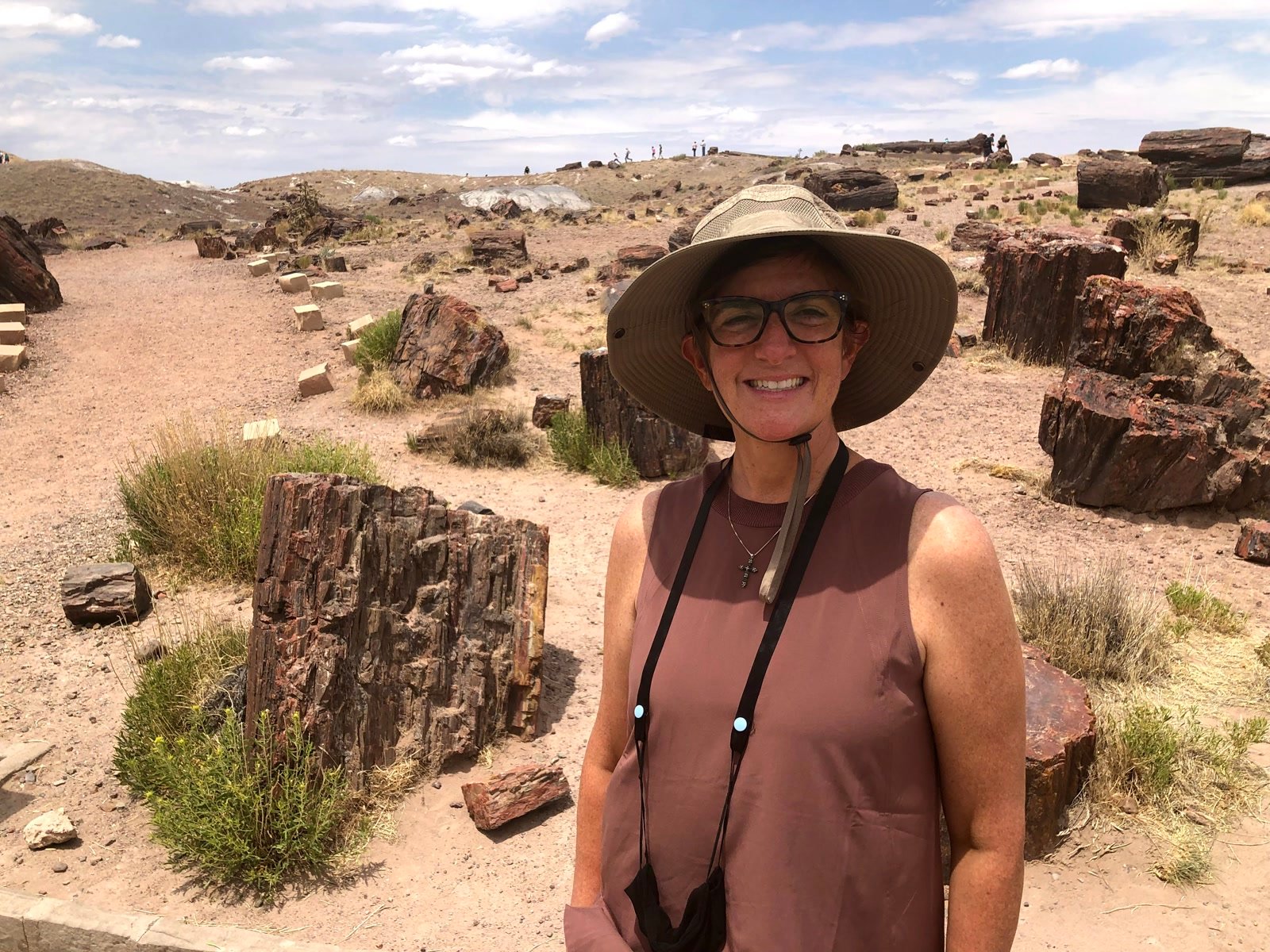 Leslie smiling among petrified wood logs