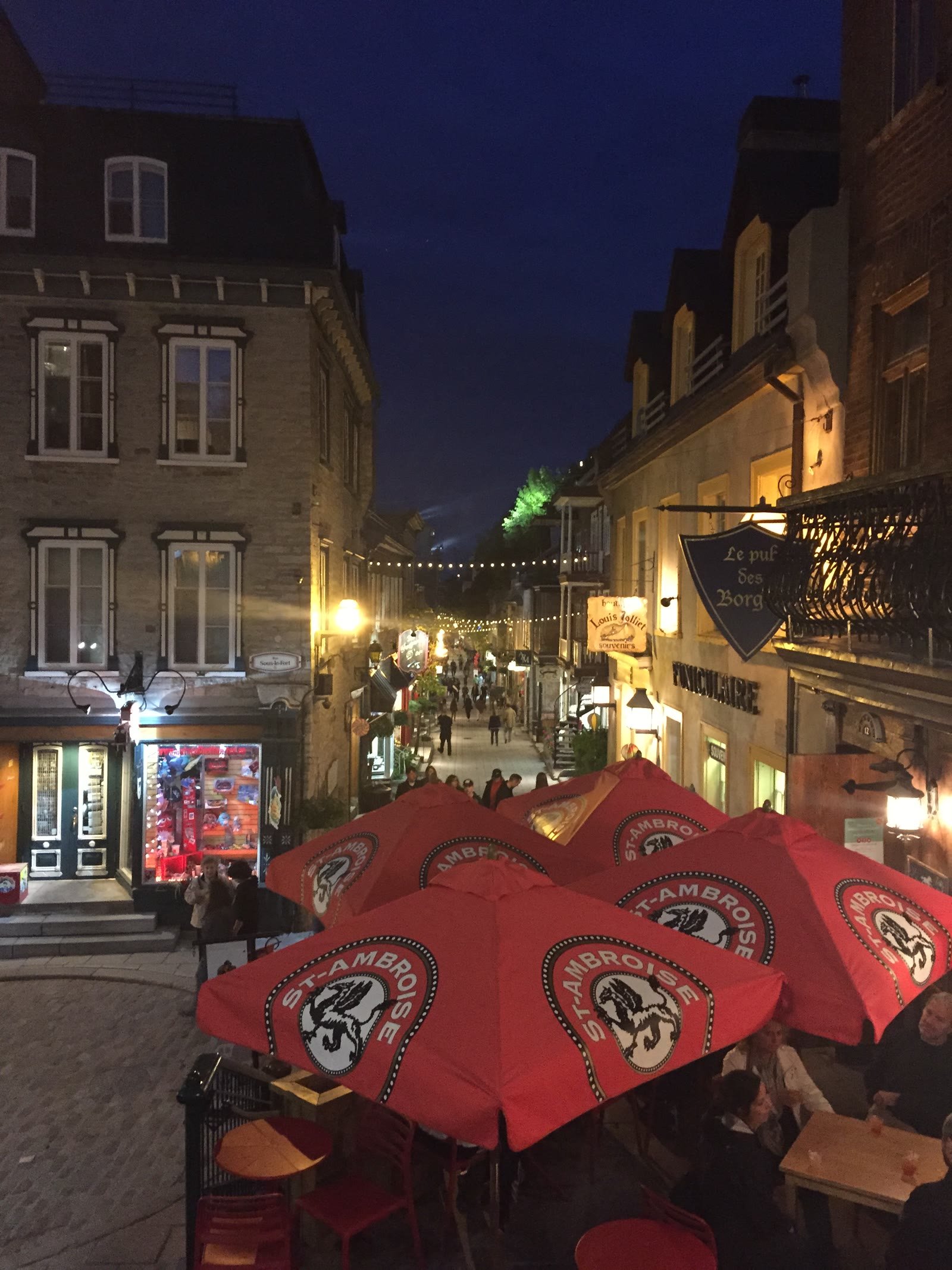 Evening street scene in Old Québec with red patio umbrellas