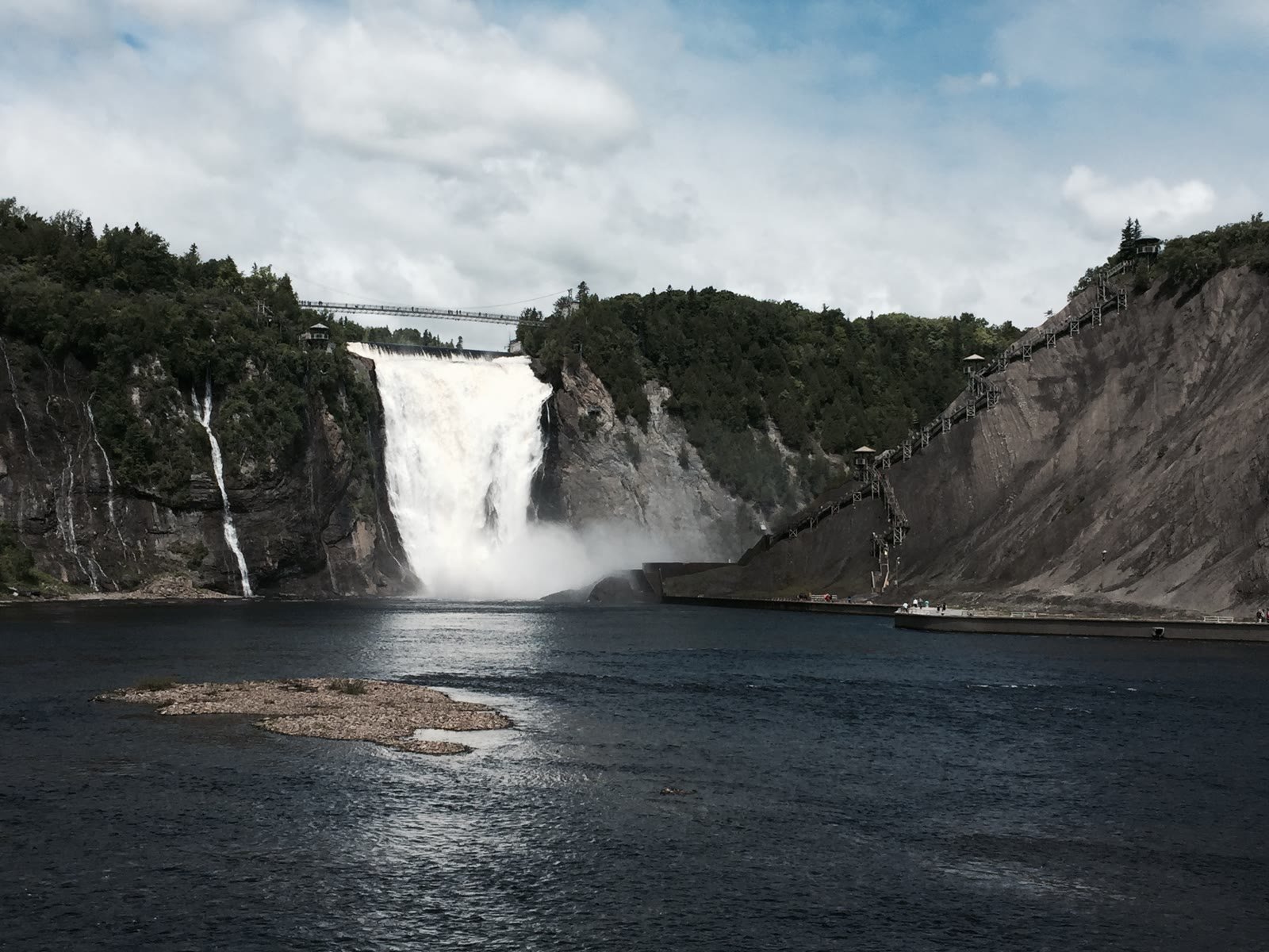 Wide waterfall with suspension bridge and cliff stairways